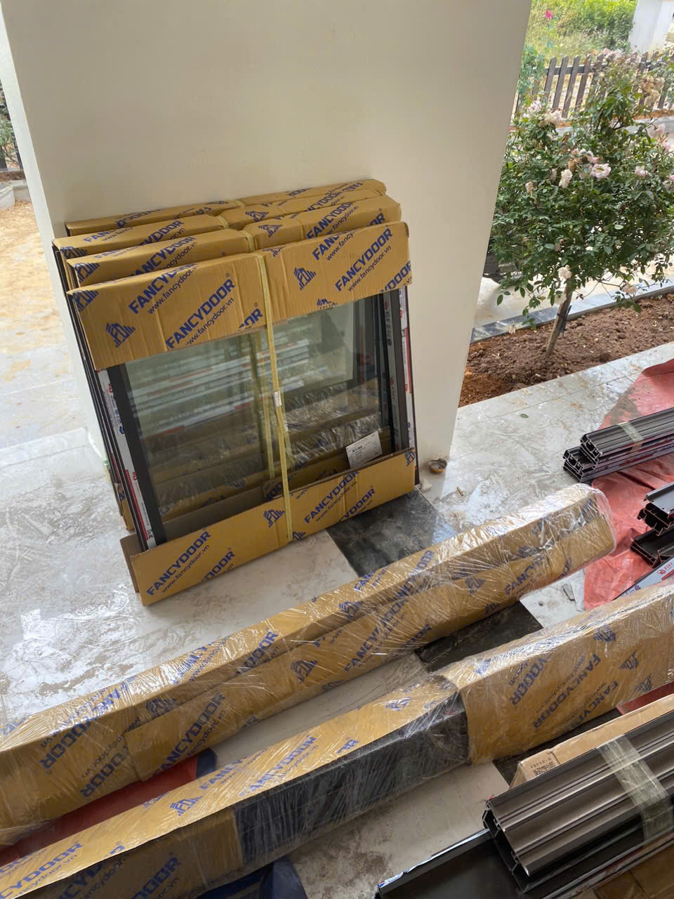 Cửa nhôm kính Fancydoor và phụ kiện đóng gói đặt trên sàn chuẩn bị lắp đặt